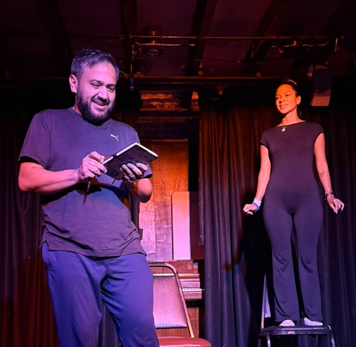 Actor reading from a notebook while an actress stands on a chair
