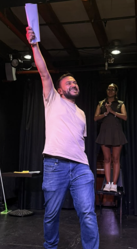 Actor raising his script in a triumphant pose on stage